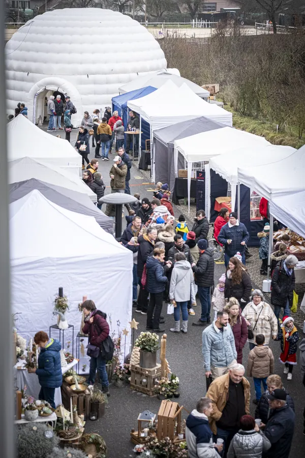 Allée du marché entre les tentes, avec les visiteurs et l'igloo gonflable au fond
