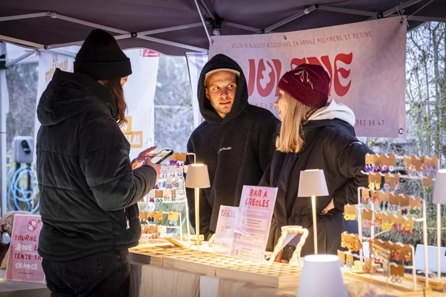 Visiteurs devant un stand de bijoux en argile polymère