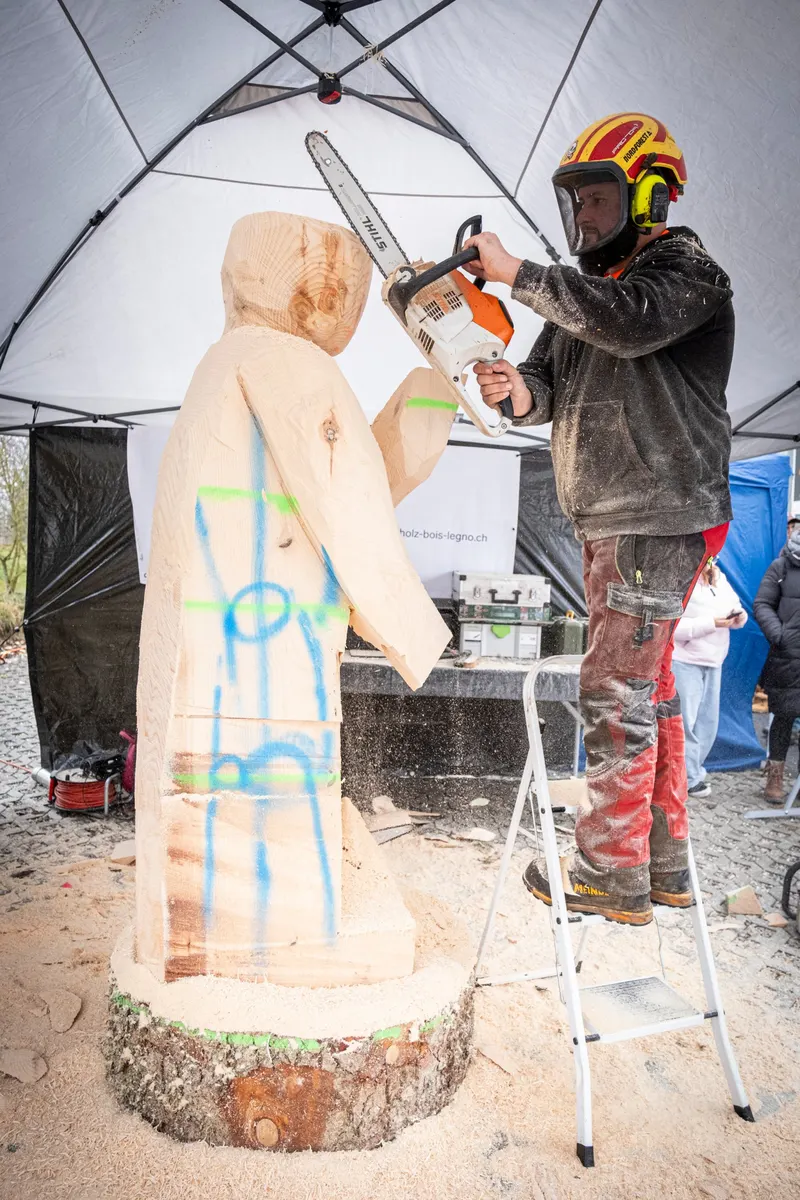 Un sculpteur taille une statue en bois à la tronçonneuse